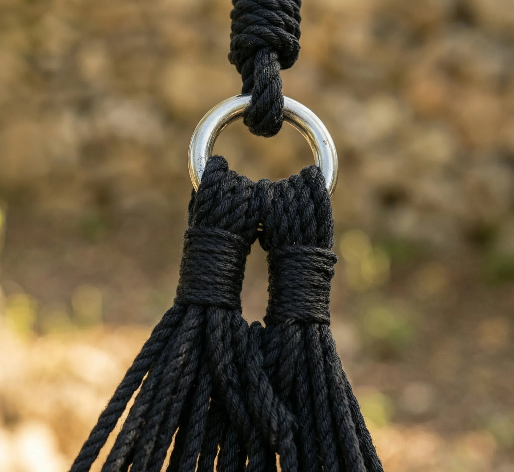 Zoom technique sur l'anneau de suspension en acier et le tressage en boucle d'un hamac noir haute résistance.