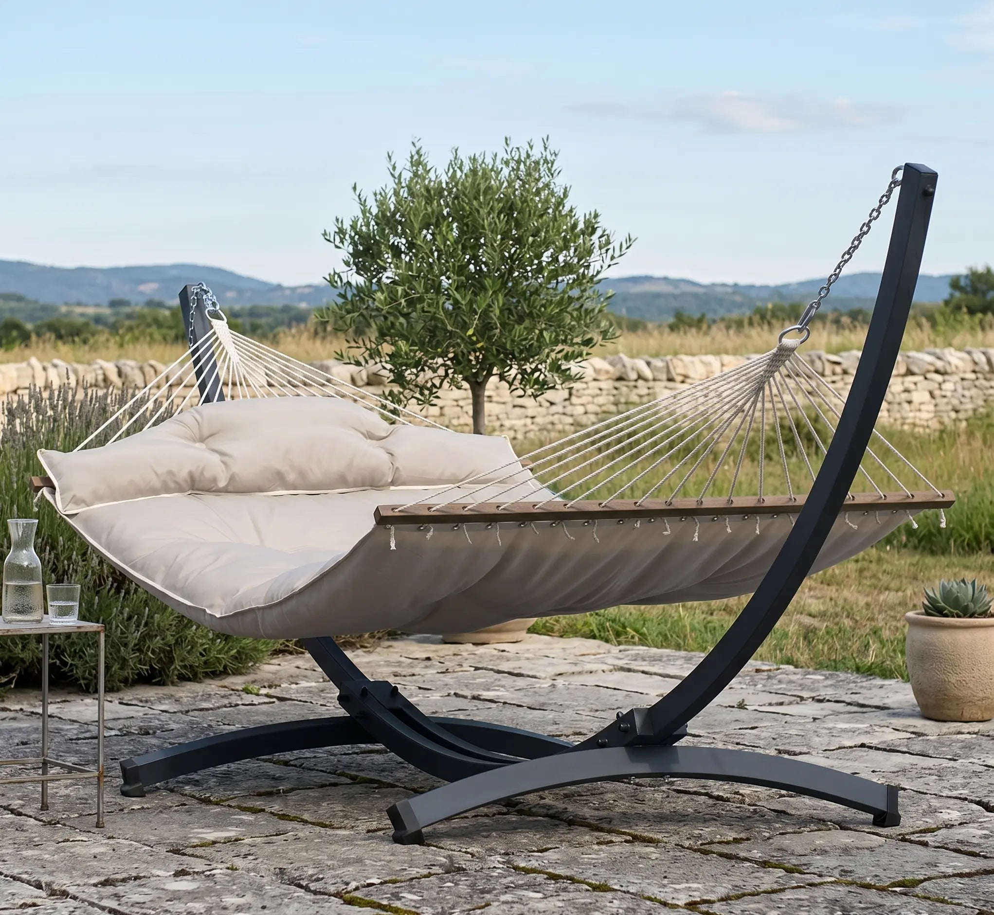 Vue de face d'une chaise hamac suspendue en tissu de coton tissé épais. Le tissu présente des rayures et un motif géométrique de chevrons répétés dans une teinte off-white (crème). Elle est ornée de franges de cordes tressées assorties sur le pourtour. La chaise est suspendue par un assemblage de cordes blanches en macramé avec des détails de perles en bois, reliées à une barre d'écartement en bois brut et un mousqueton métallique. Isolé sur un fond blanc pour un rendu produit clair et détaillé.
