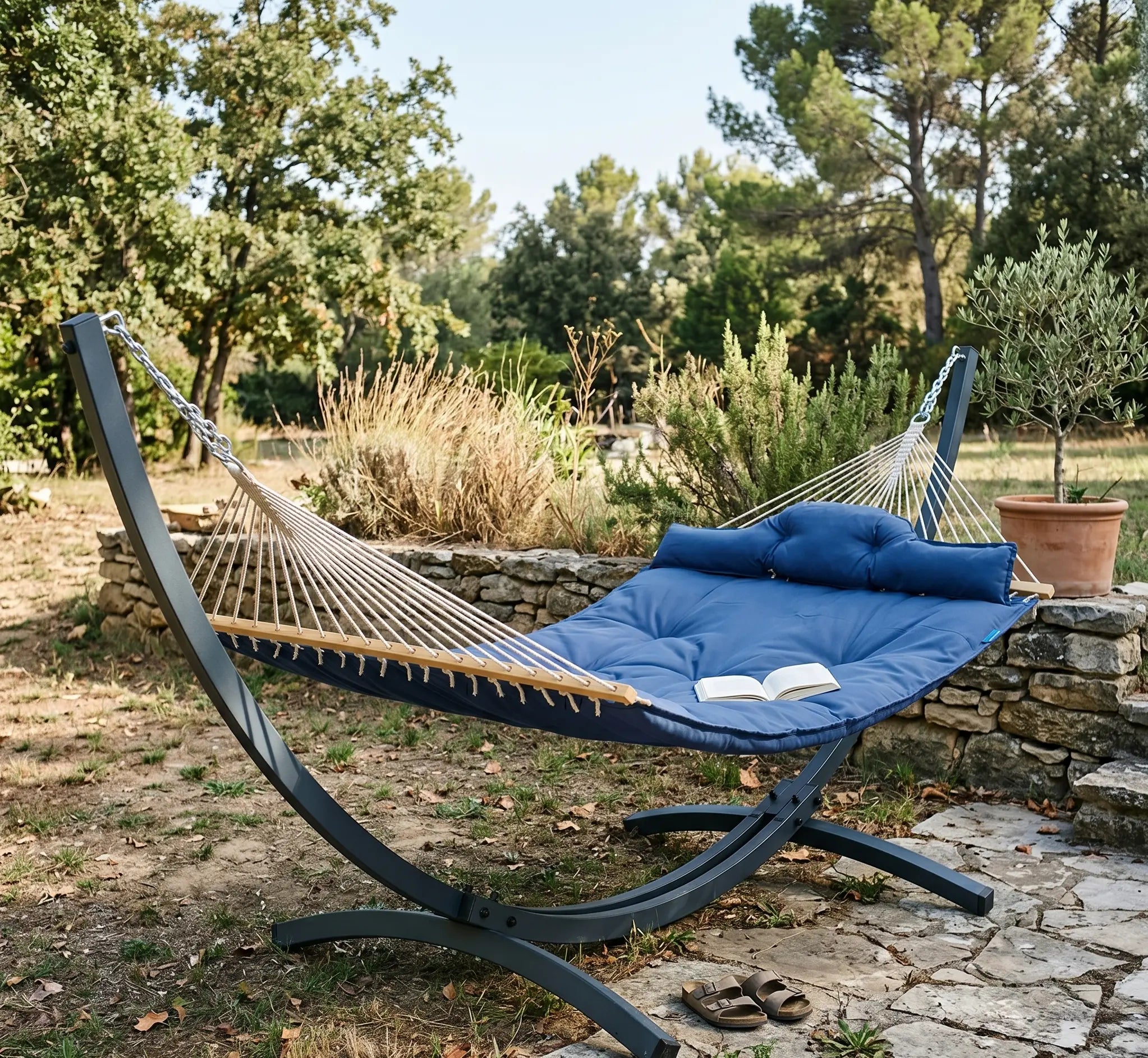 Vue de face d'une chaise hamac suspendue en tissu de coton tissé épais. Le tissu présente un motif géométrique de chevrons répétés de couleur rouge bordeaux et off-white (crème). Elle est suspendue par un assemblage de cordes blanches en macramé avec des détails de perles en bois, reliées à une barre d'écartement en bois brut et un mousqueton métallique. Isolé sur un fond blanc pour un rendu produit clair et détaillé.