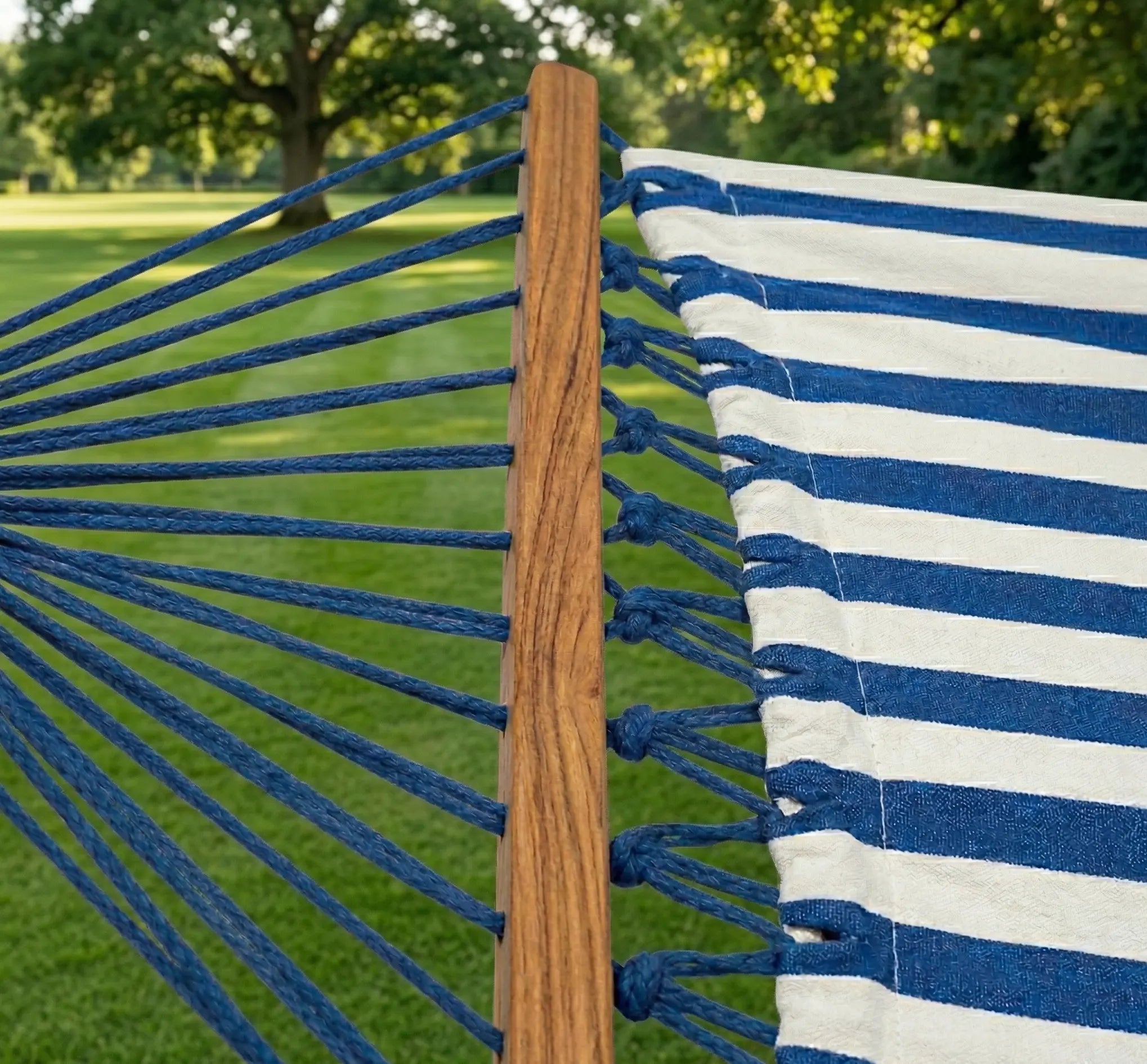Zoom sur la barre d'écartement en bois massif et les cordages de suspension bleus d'un hamac de jardin robuste.