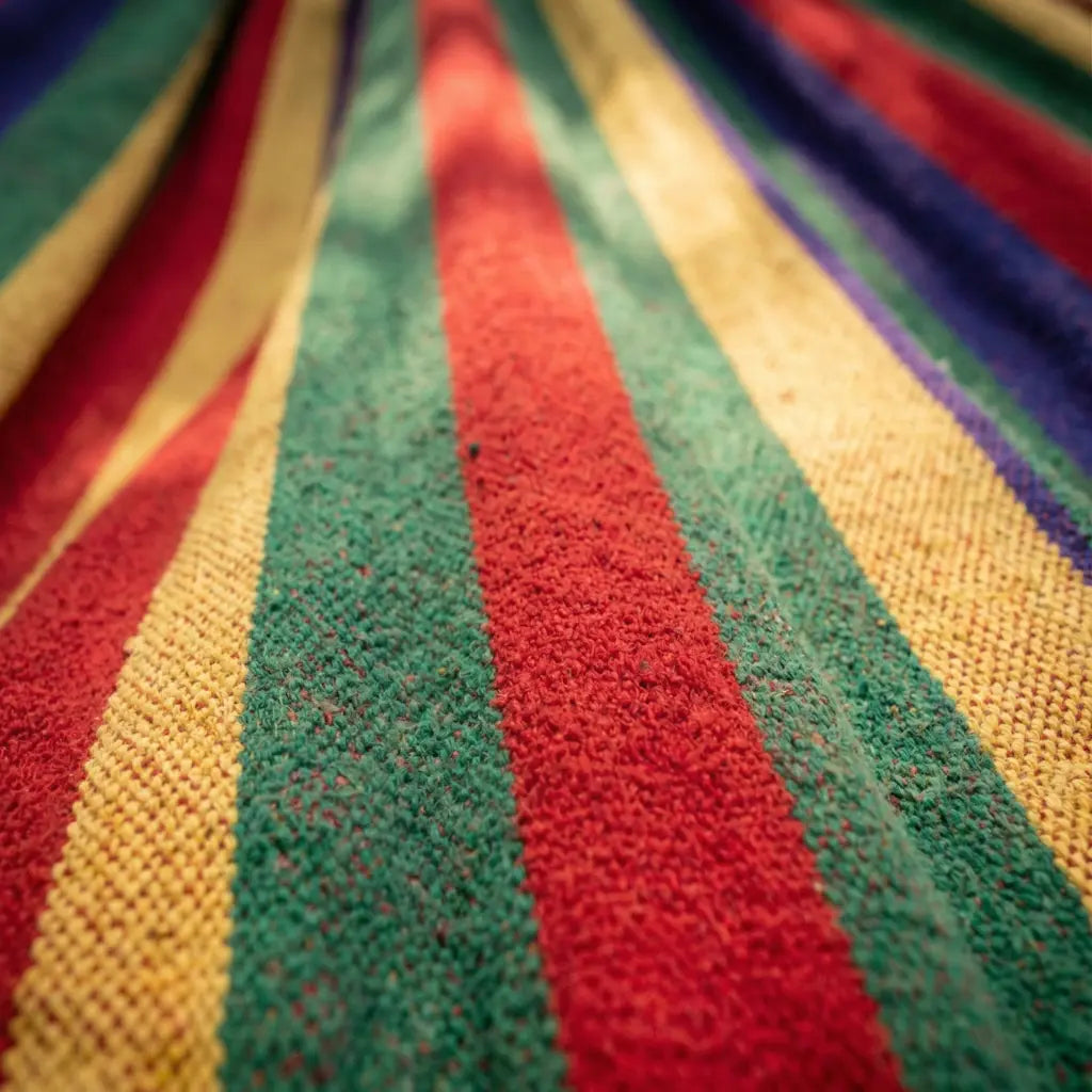 Gros plan sur les cordages de suspension rouges et les finitions tissées d'un hamac de jardin multicolore.