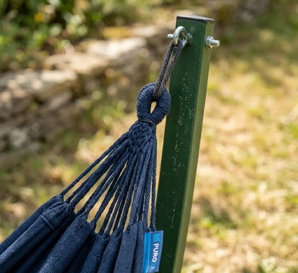 Zoom technique sur le crochet de fixation en acier galvanisé et la boucle de suspension tressée d'un hamac bleu marine sur son montant en acier vert forêt