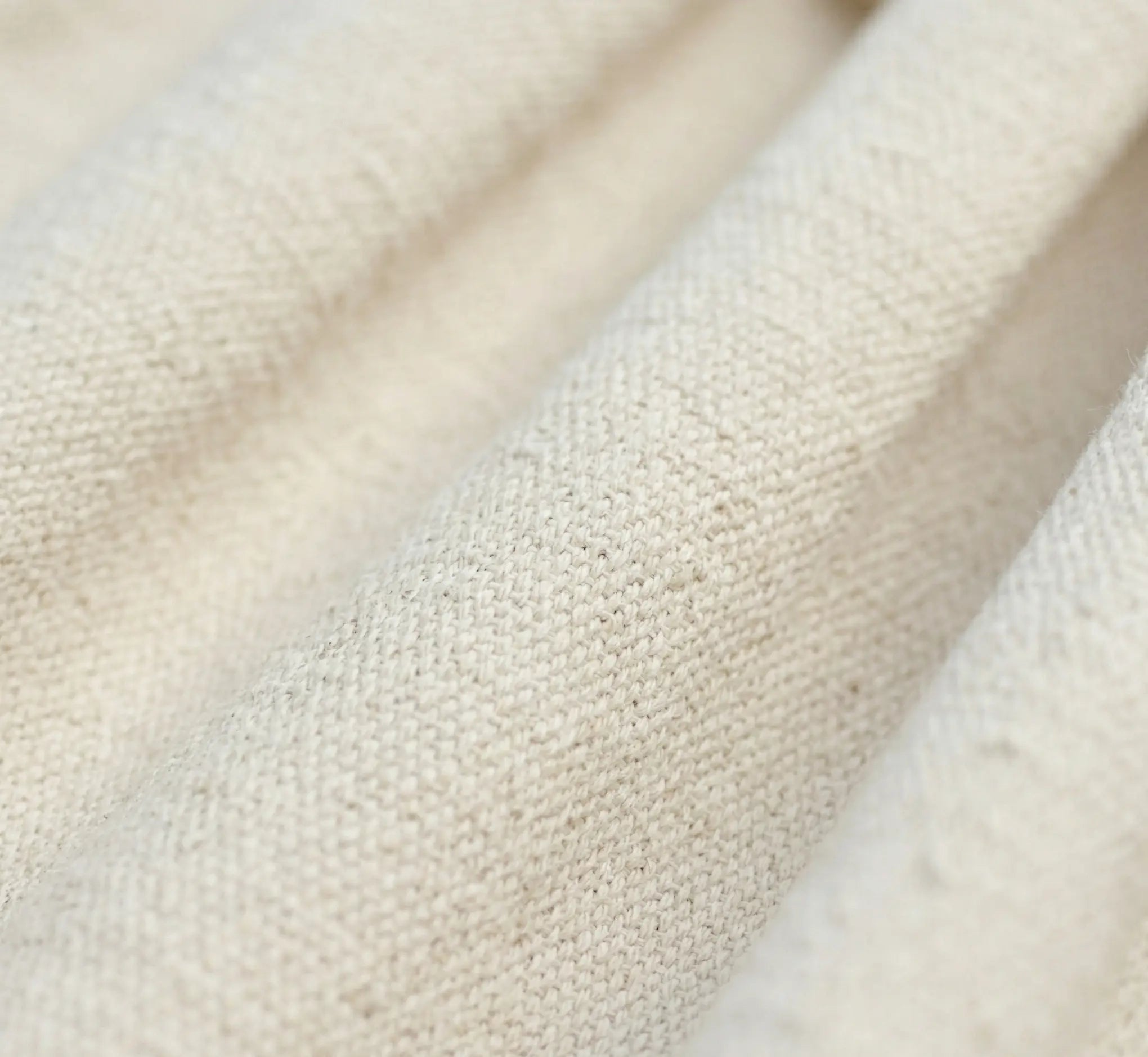 Gros plan sur les franges délicates en macramé tressées à la main et les pompons décoratifs d'un hamac de luxe en coton écru naturel.