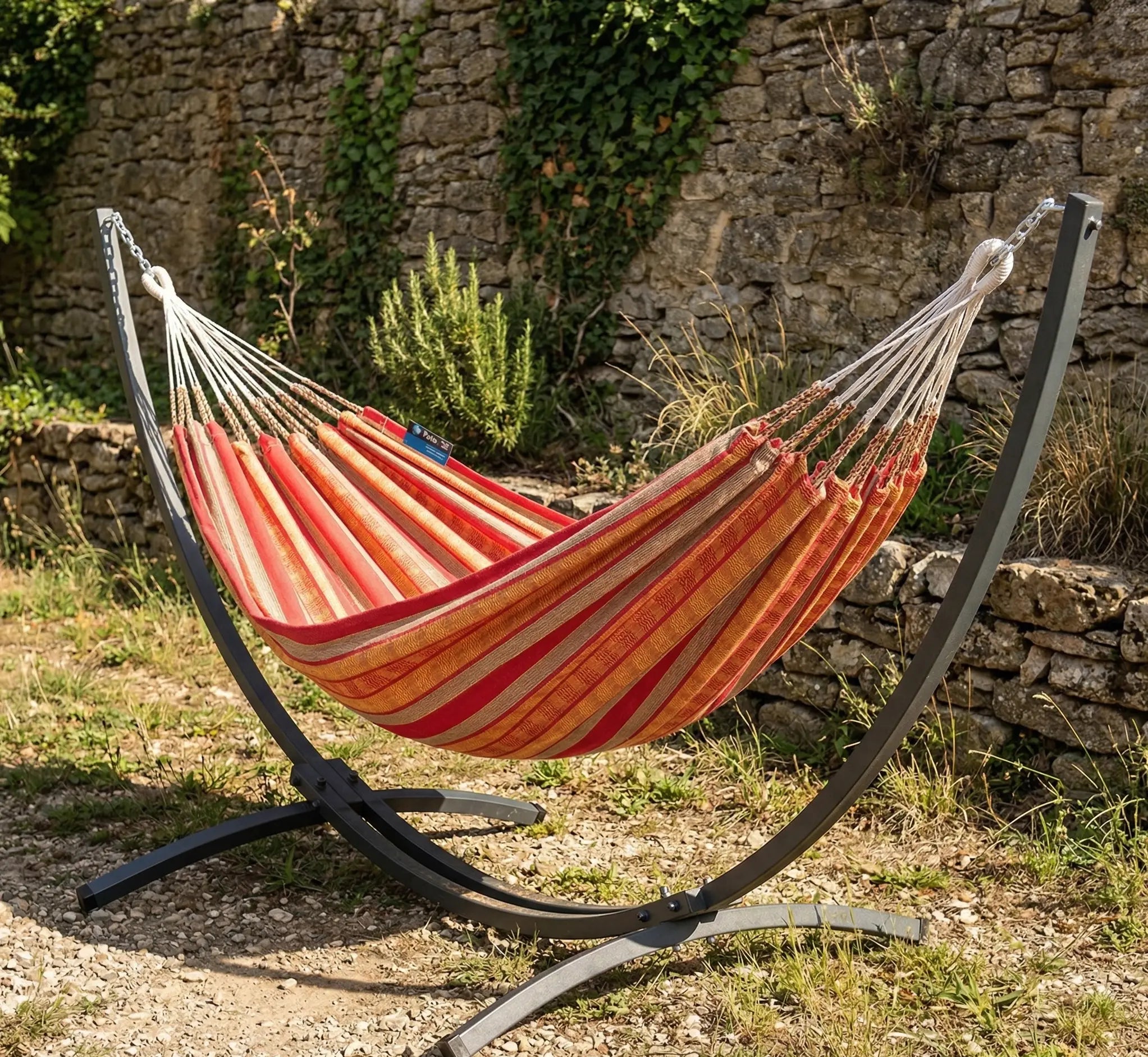 Zoom technique sur le point d'ancrage et la structure en acier noir courbé d'un hamac design avec toile en coton premium aux rayures terracotta et ocre jaune style méditerranéen