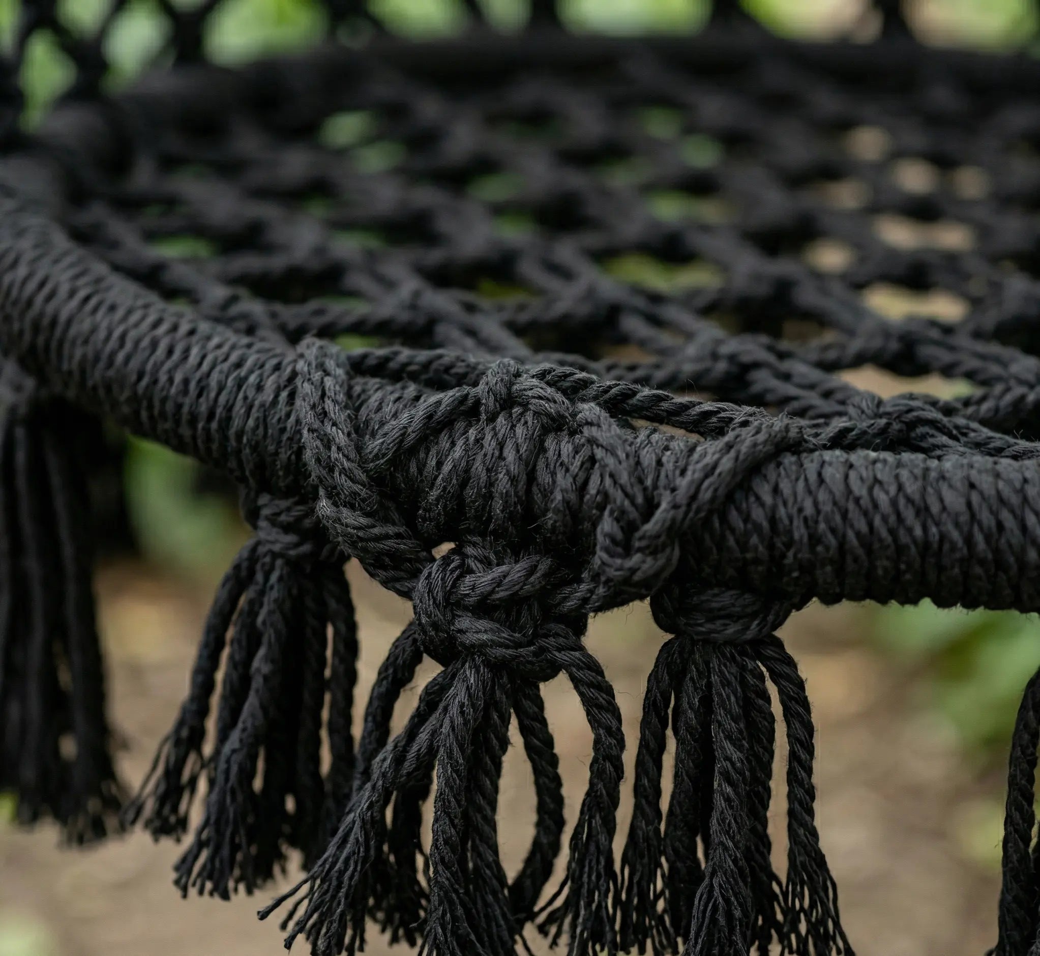 Détail du kit de fixation robuste pour fauteuil suspendu avec support en acier noir et boucle de cordage tressée haute résistance fixée à une branche