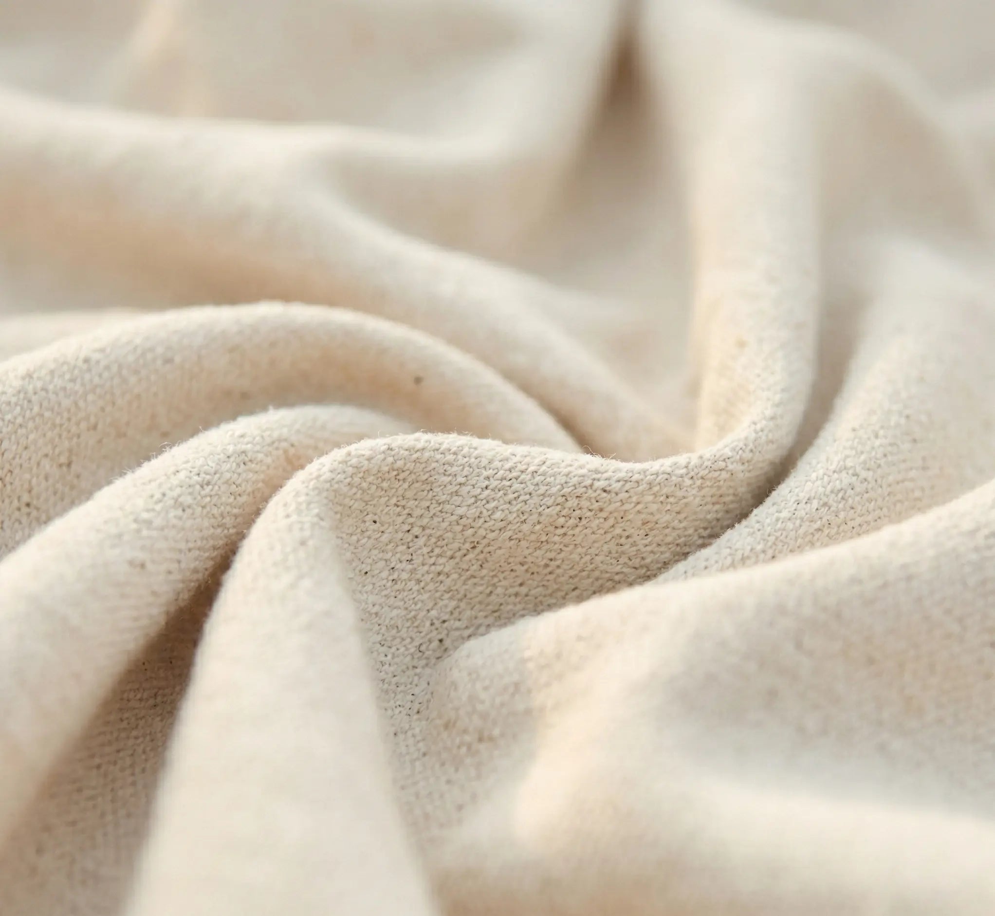 Vue macro du drapé d'une toile de hamac en coton naturel écru montrant la douceur du tissage et la qualité des fibres textiles haut de gamme