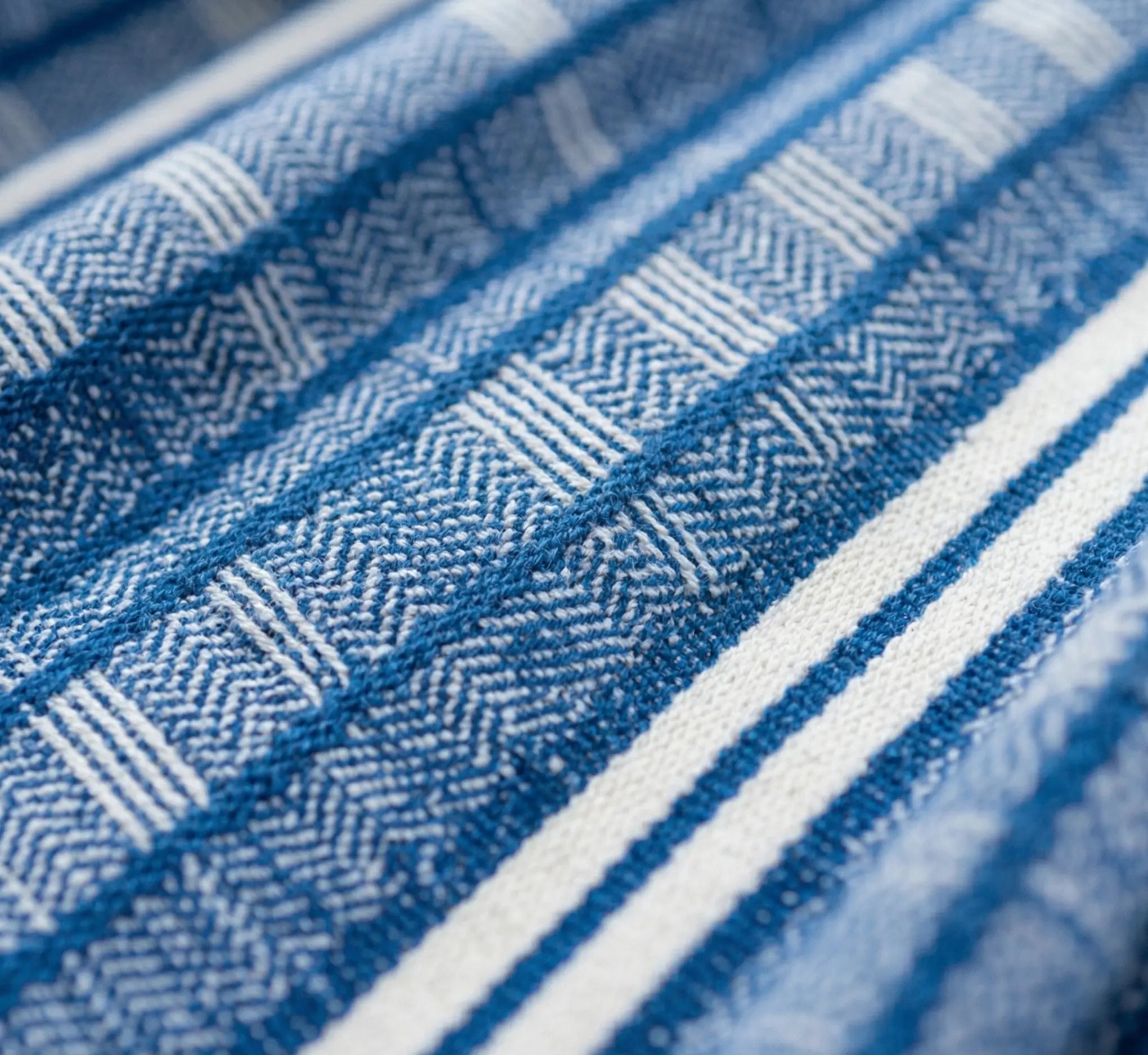Vue macro haute résolution du tissage d'une toile de hamac en coton premium montrant l'entrelacement serré des fibres bleues et blanches de haute densité