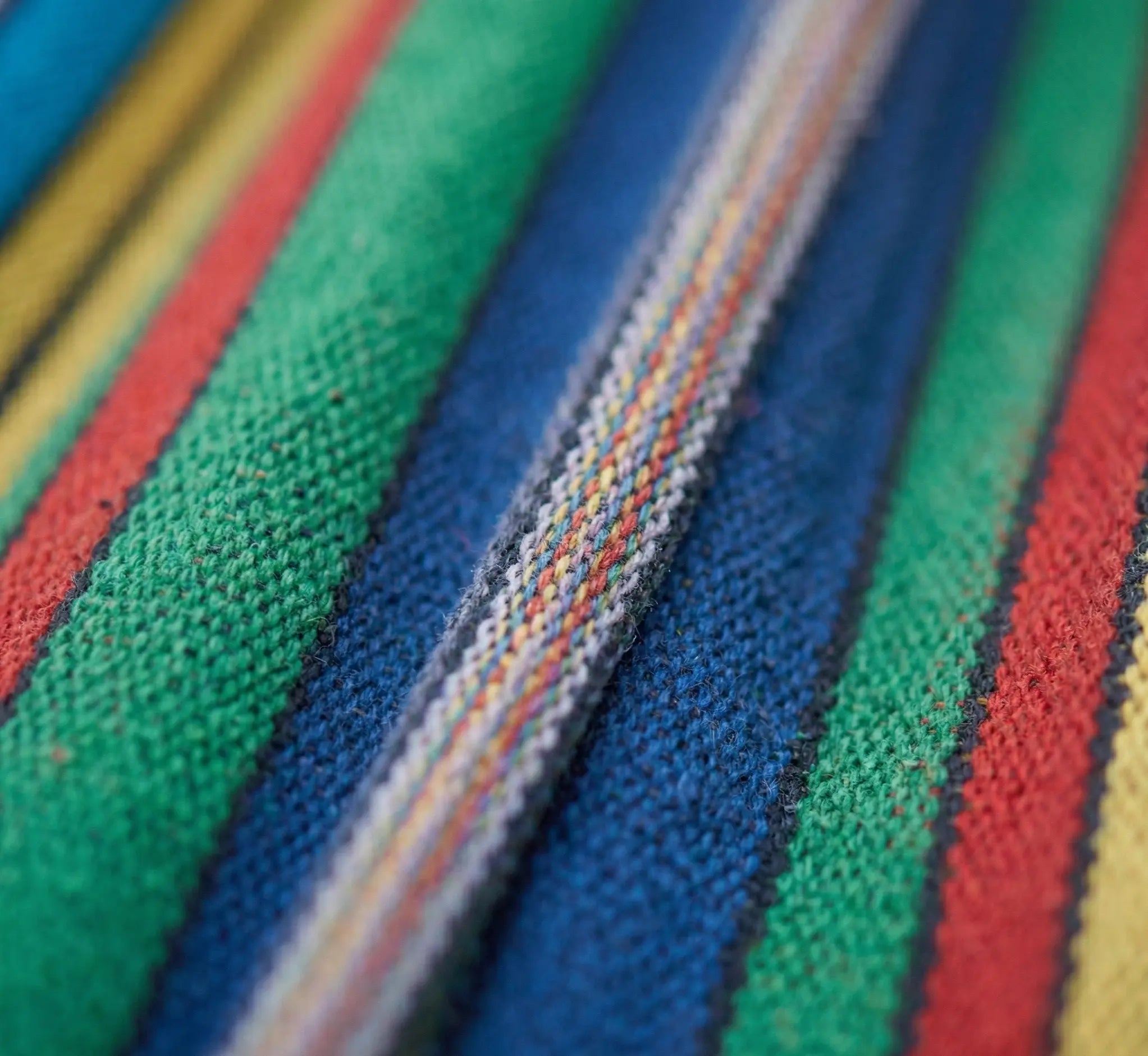 Vue macro du grain de tissage d'un hamac en coton naturel haute densité montrant les fibres entrelacées multicolores pour un confort durable et haut de gamme