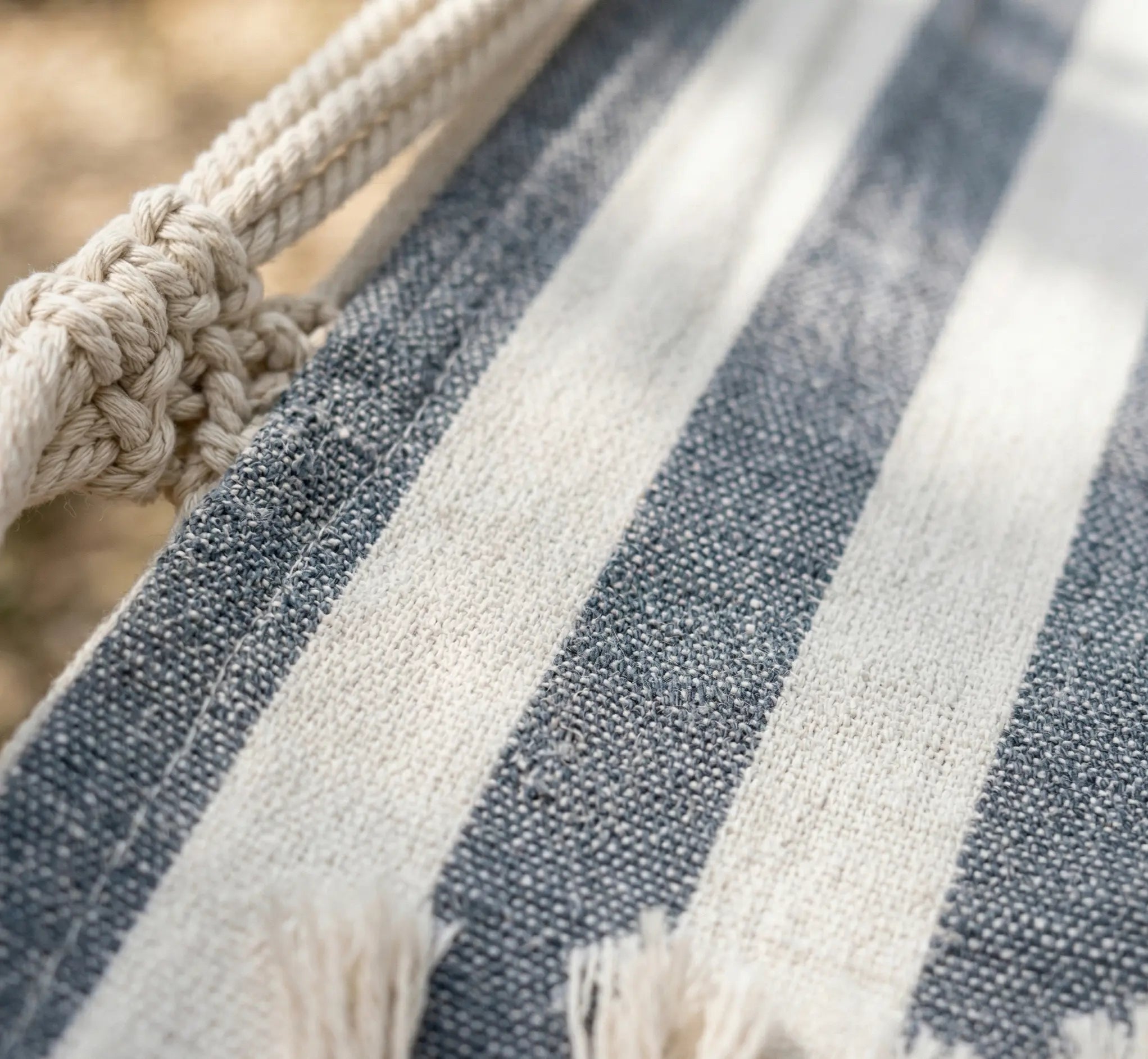 Zoom sur le tissage serré et la toile épaisse en coton d'un hamac haut de gamme aux rayures gris anthracite et blanc.