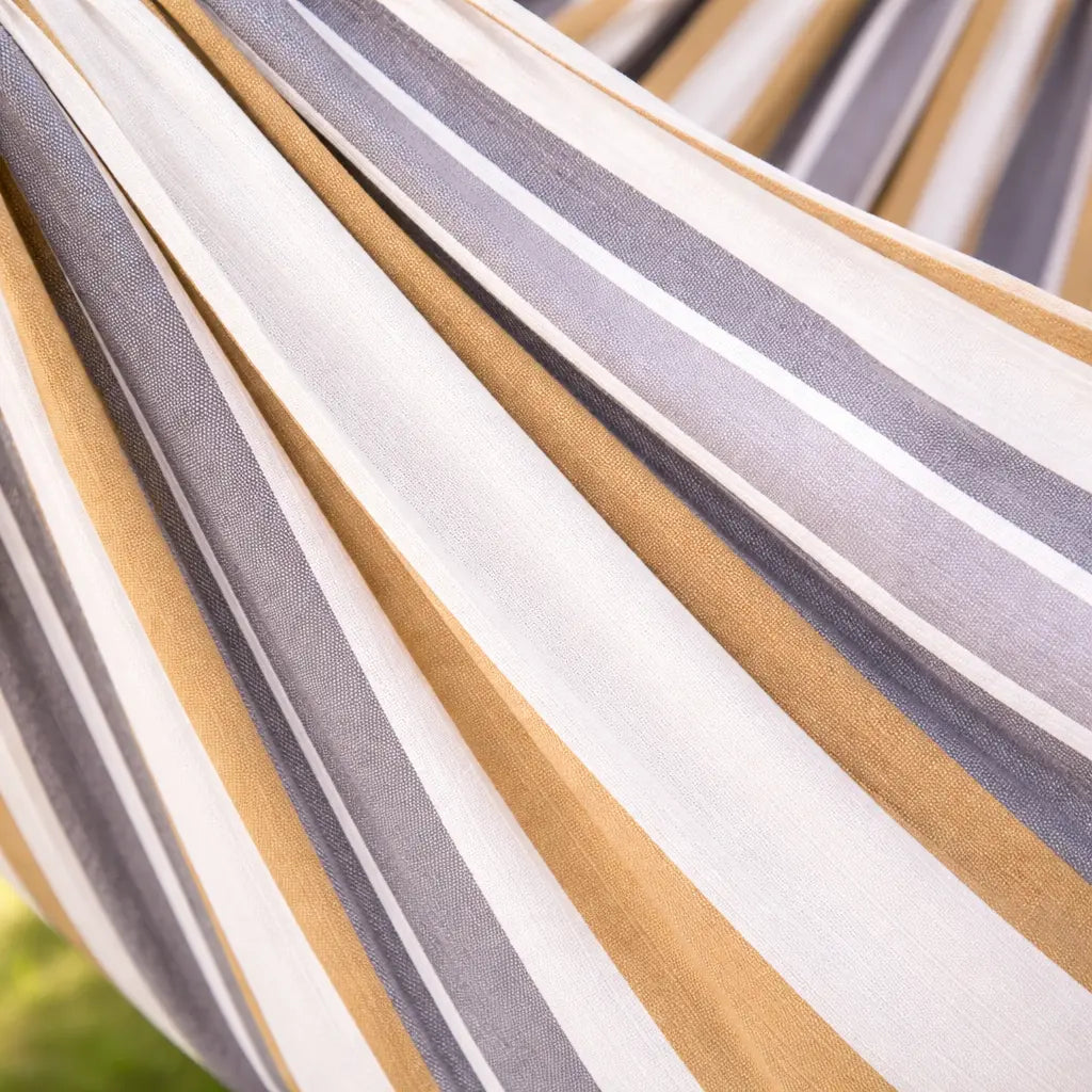 Gros plan sur le tissage de haute qualité d'une toile de hamac aux rayures verticales gris, jaune moutarde et blanc.