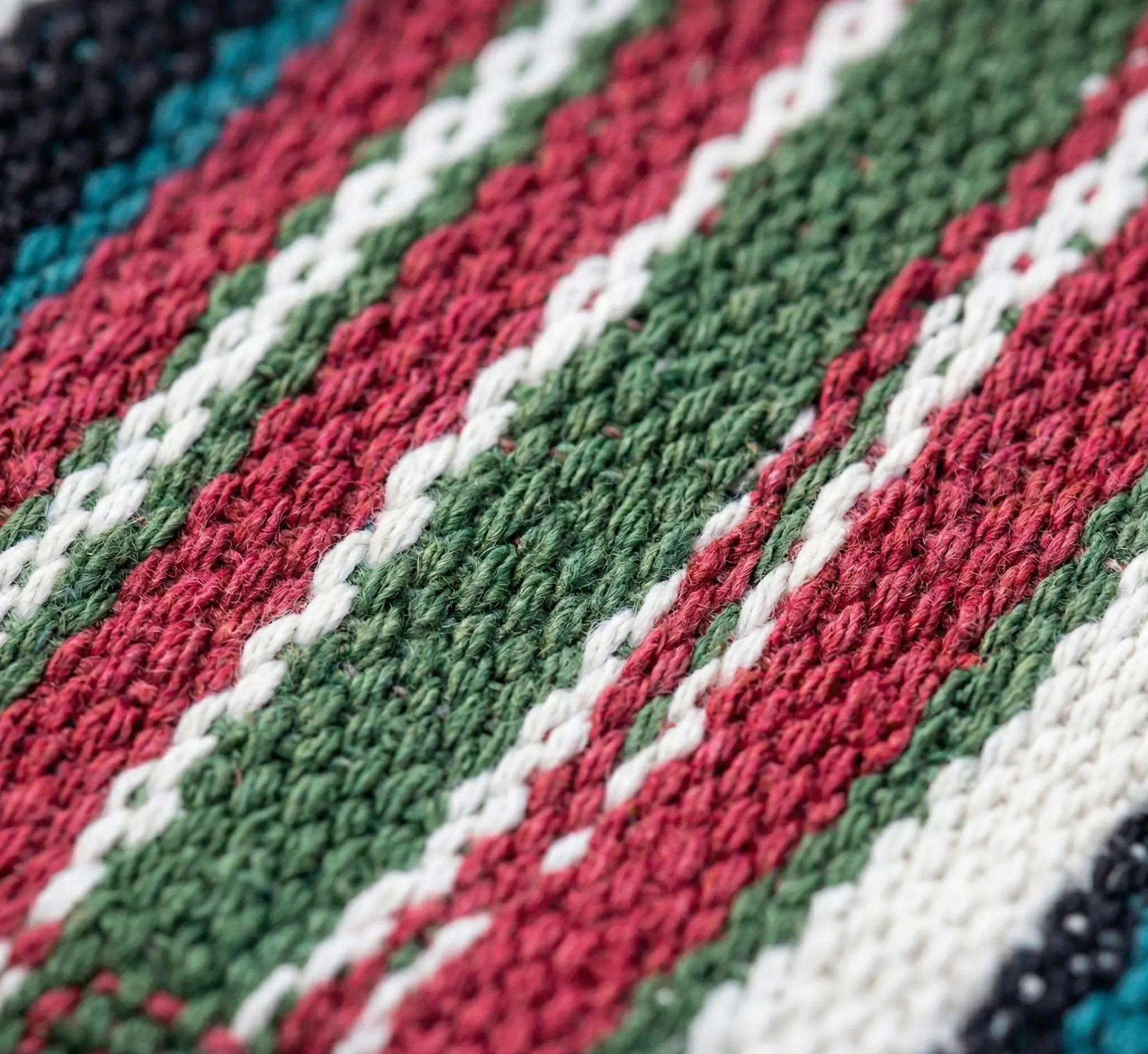 Gros plan sur le tissage jacquard dense et les fibres de coton de haute qualité d'un hamac aux rayures bordeaux vert et bleu.