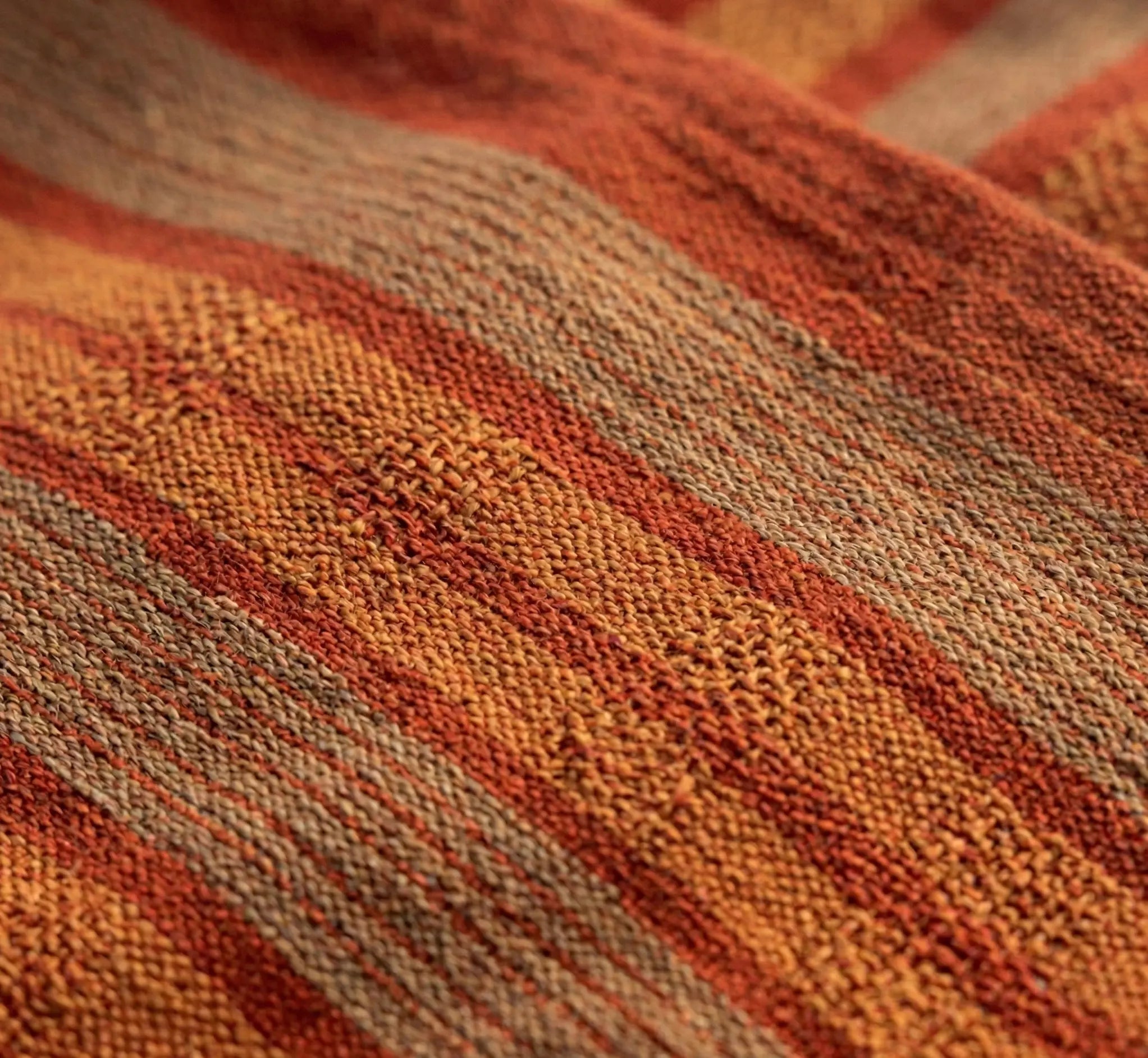 Très gros plan sur le tissage dense d'une toile de hamac à rayures rouges et orange, montrant la texture du coton renforcé et la qualité des finitions textiles