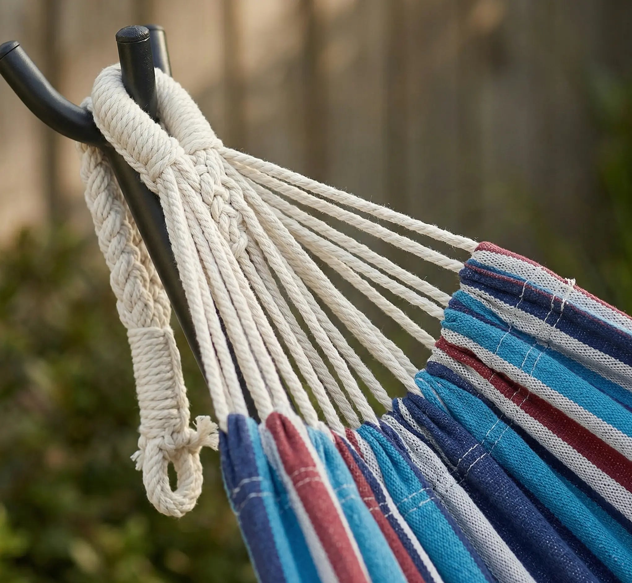 Gros plan sur les cordes de suspension en coton tressé main fixées à un crochet de support en acier noir illustrant la finesse du travail artisanal et la sécurité du hamac
