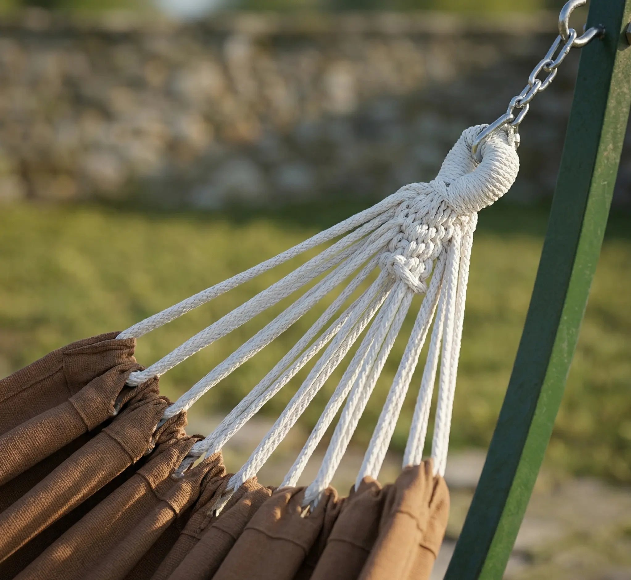 Gros plan sur la chaîne en acier galvanisé et le noeud de suspension renforcé d'un hamac marron chocolat installé sur un support en acier vert forêt robuste