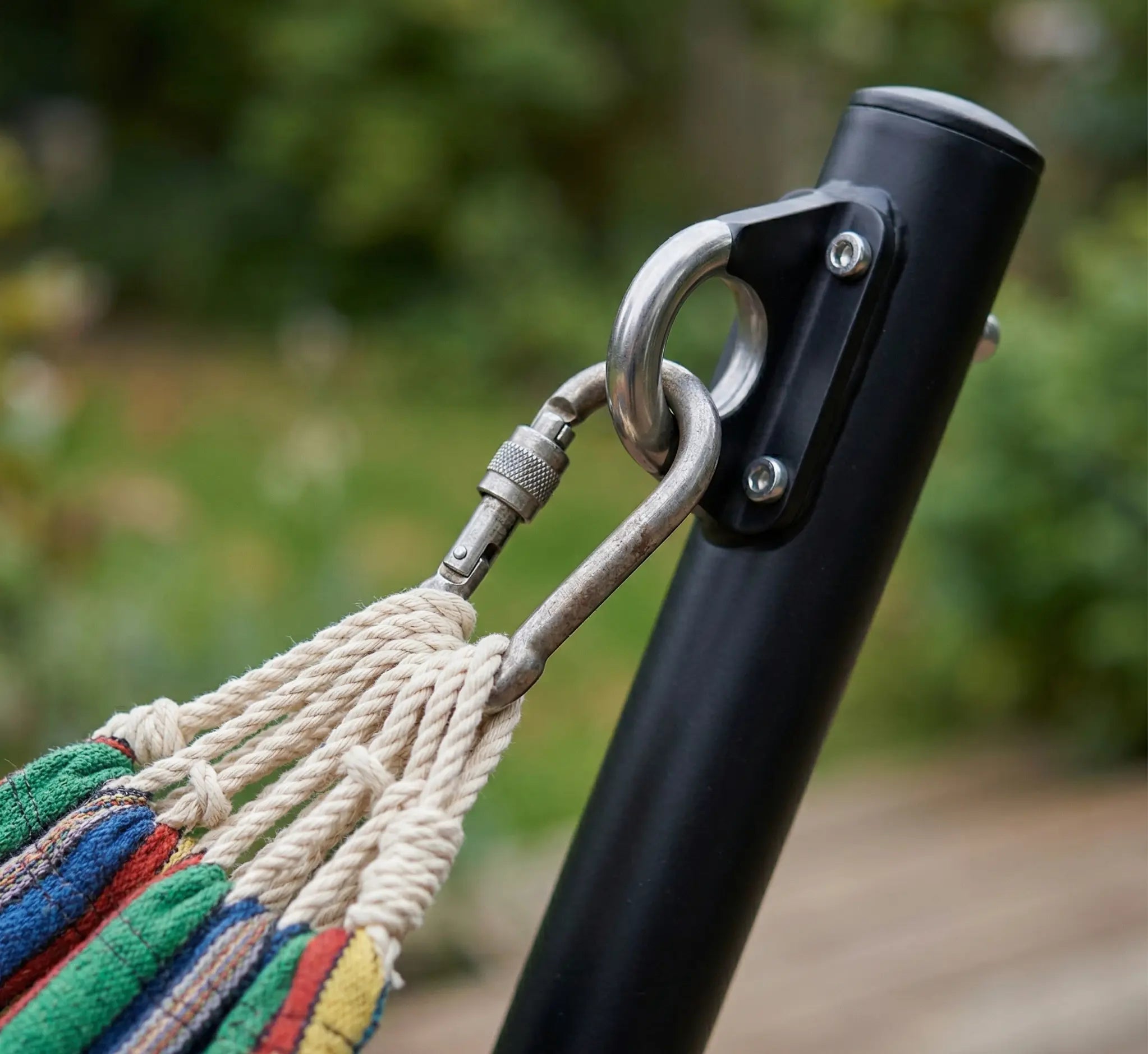 Gros plan technique sur le système de suspension d'un hamac de luxe montrant un mousqueton de sécurité en acier inoxydable relié à un anneau sur support en acier noir