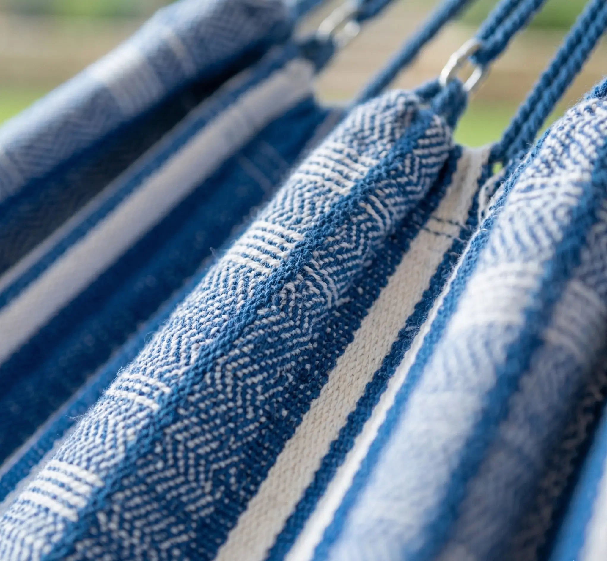 Zoom sur le point d'ancrage et la structure en acier noir courbé d'un hamac design avec toile en coton premium aux rayures bleues et blanches style nautique