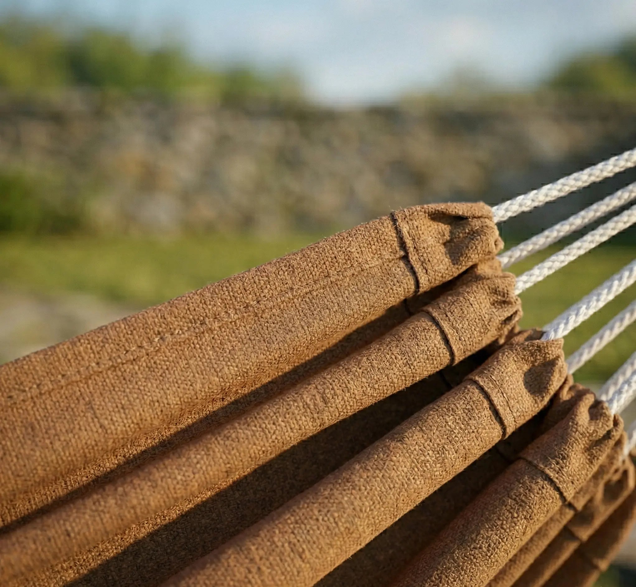 Zoom sur les coutures renforcées et l'ourlet de finition d'un hamac en coton marron chocolat de haute densité montrant la qualité de fabrication premium