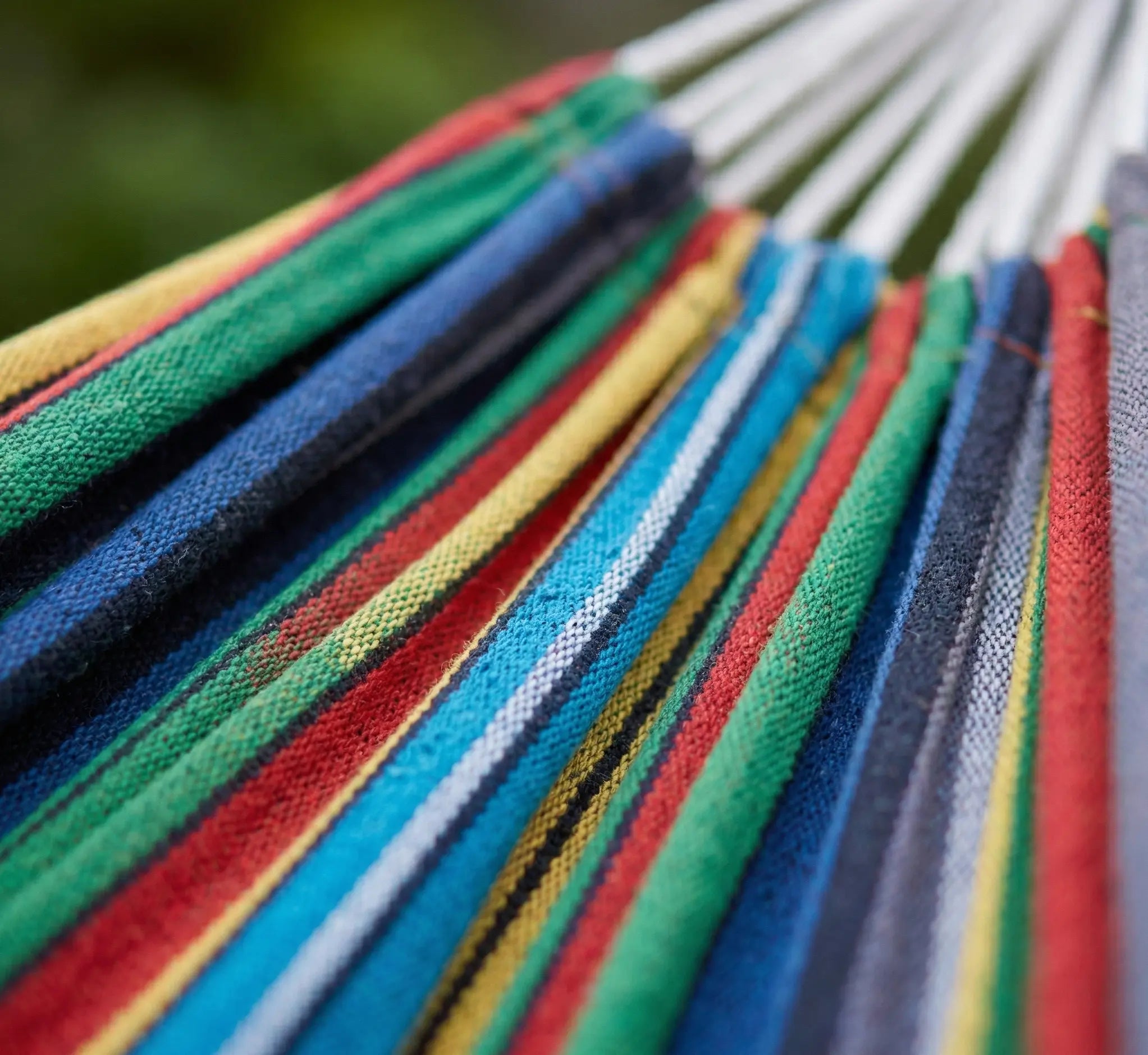 Détail du tissage dense en coton naturel d'un hamac haut de gamme aux rayures multicolores jaune vert rouge et bleu avec cordes de suspension blanches robustes