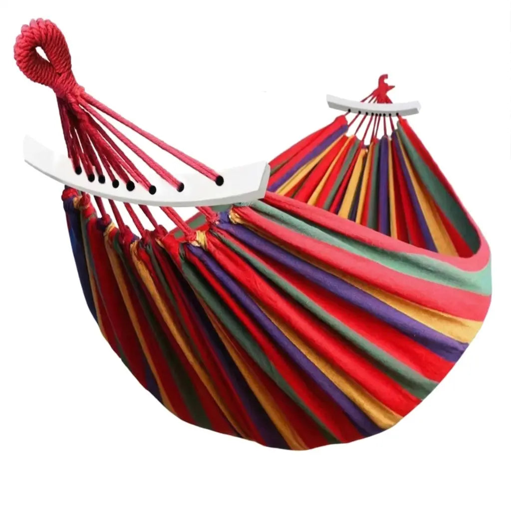 Hamac de jardin XL aux rayures multicolores arc-en-ciel avec barres d'écartement blanches et cordages de suspension rouges.
