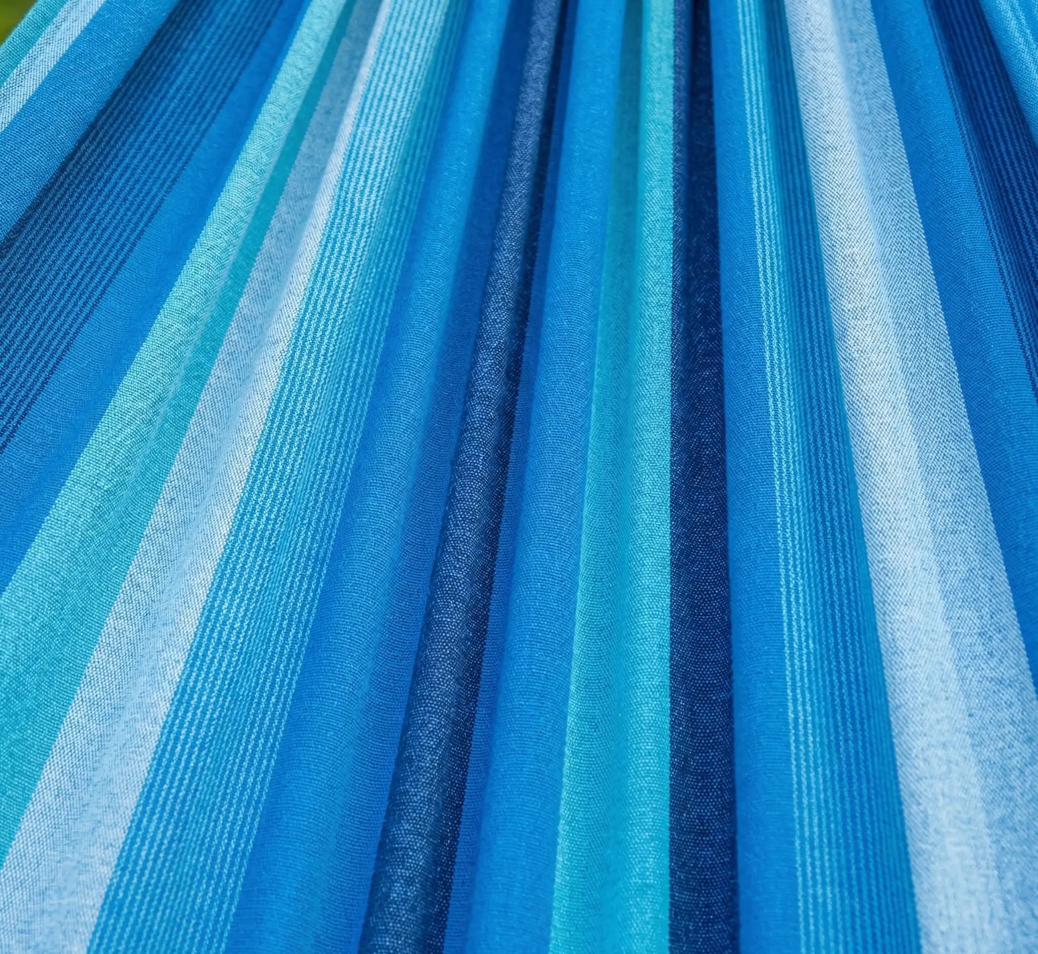 Vue macro haute résolution du tissage d'une toile de hamac en coton premium montrant des rayures en dégradé bleu lagon, bleu turquoise et bleu marine