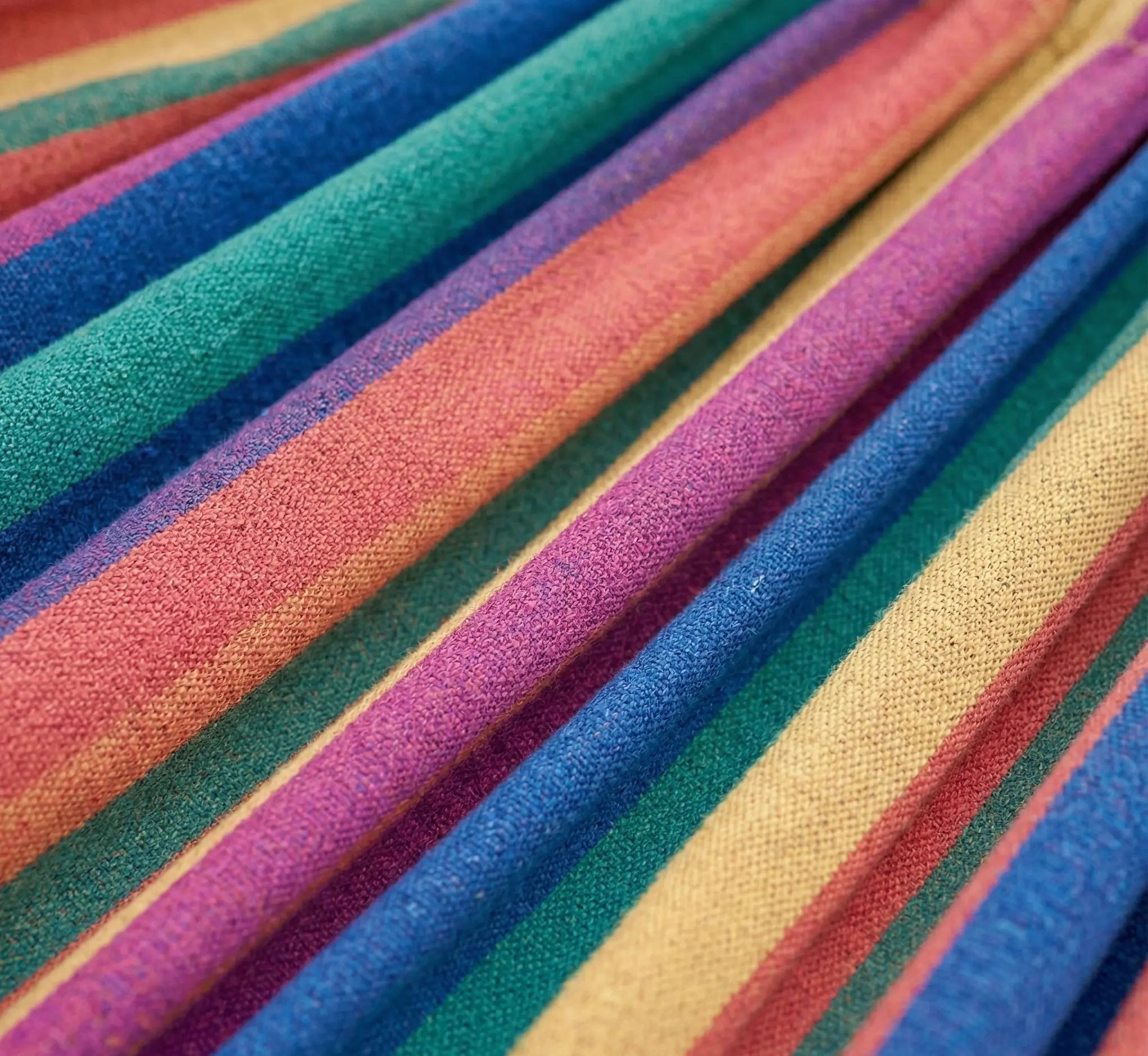 Vue macro haute précision du grain de tissage d'une toile de hamac en coton naturel montrant la densité des fibres aux rayures ocre jaune violet et turquoise