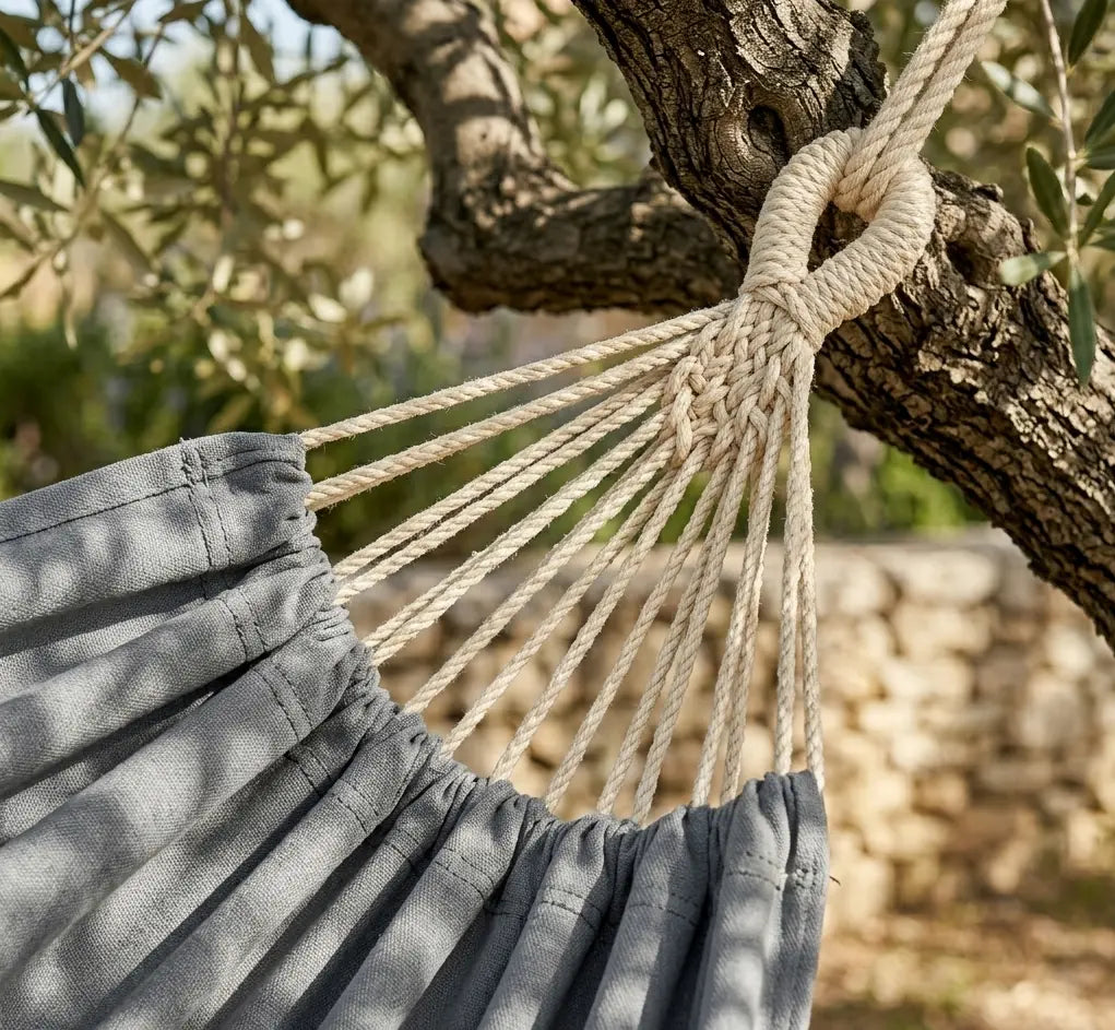 Gros plan sur les cordes de suspension blanches tressées et le nœud de fixation robuste d'un hamac en coton gris anthracite.